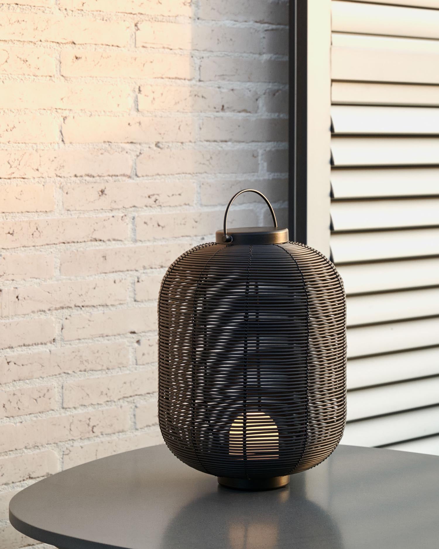 Die Saranella Tischlampe von Kave Home ist eine elegante, tragbare Leuchte aus schwarzem Kunstrattan, ideal für stilvolle Beleuchtung überall.