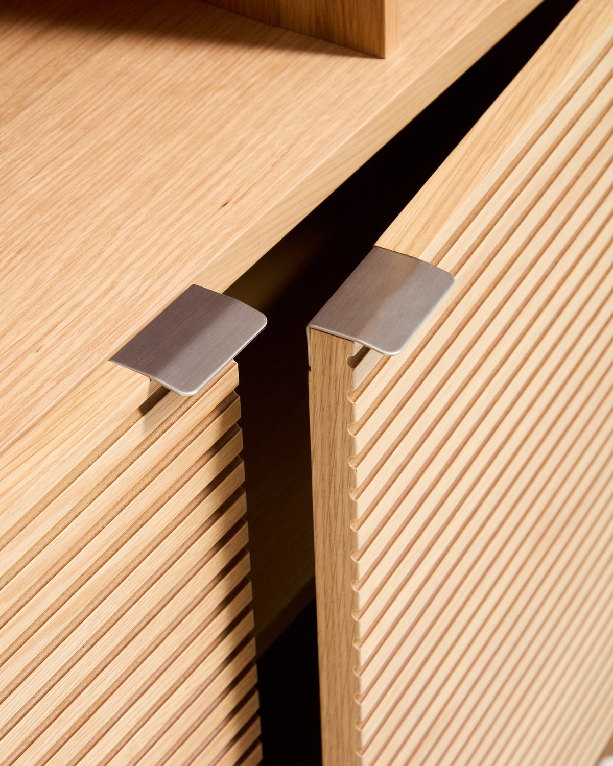 Braunes Highboard Norlen mit 4 Türen aus Eichenfurnier und MDF, naturfarbenes Finish, abgerundete Ecken, Beinhöhe 14 cm.