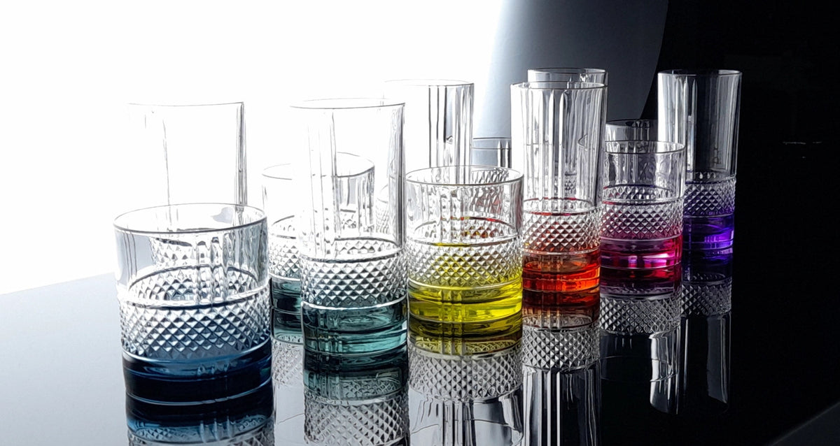 Sechs mehrfarbige Dof Trinkgläser aus Glas der RCR Brillante Color-Serie, je 34 cl, nebeneinander auf einer hellen Fläche aufgestellt.