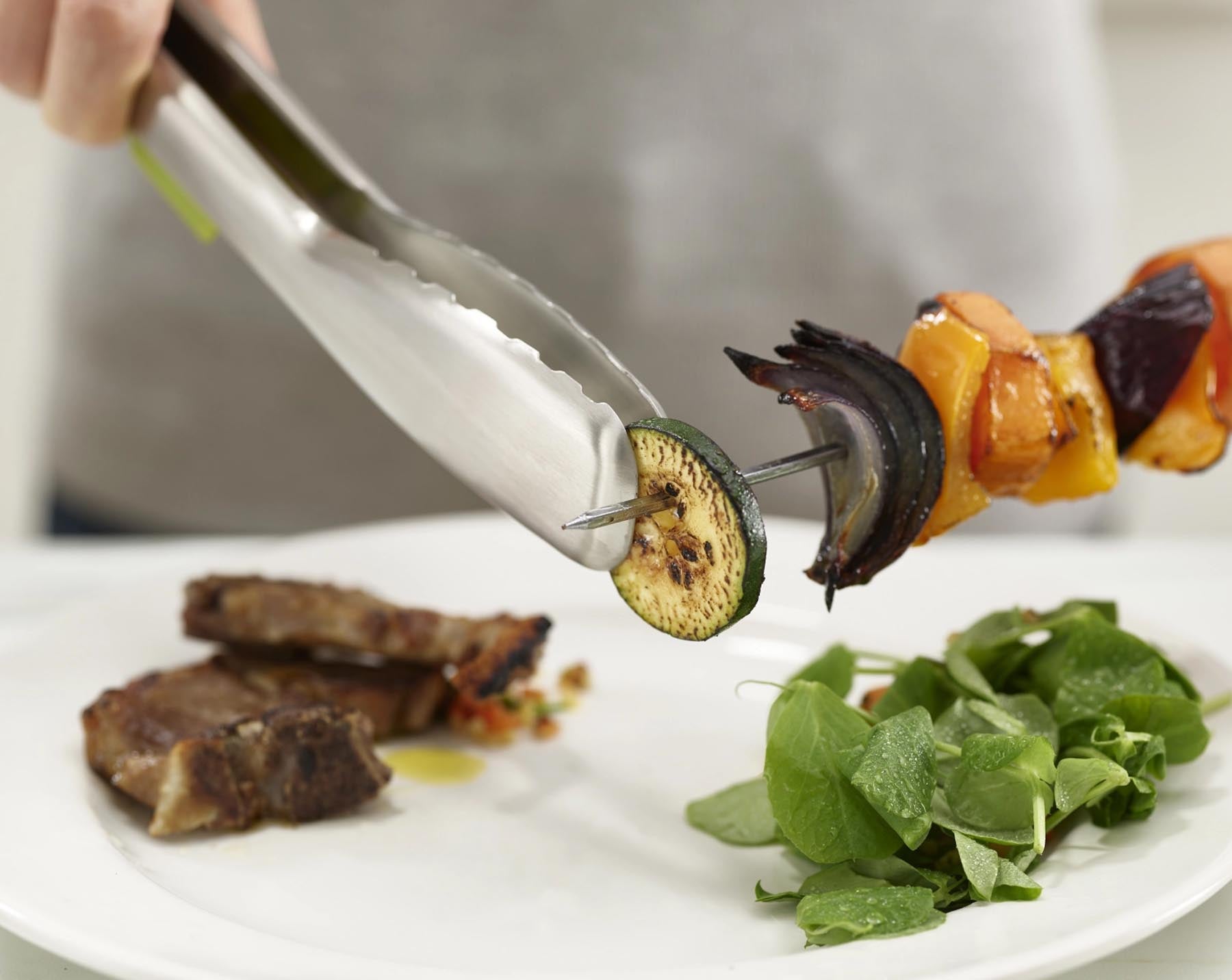 Moderne Edelstahlzange in ansprechendem Grün, ausgestattet mit praktischen integrierten Auflagen für komfortables Kochen und Servieren.