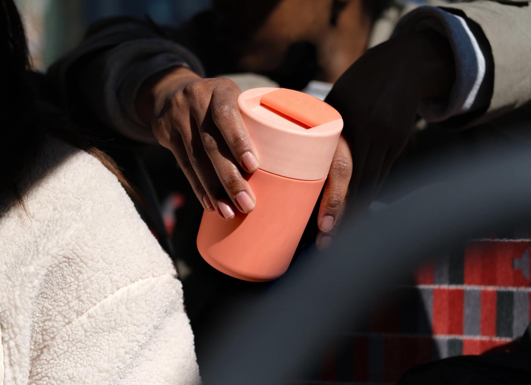 Eleganter Sipp Reisebecher in leuchtendem Koralle, ausgestattet mit einem funktionalen Klappdeckel – ideal für alle Getränke unterwegs.
