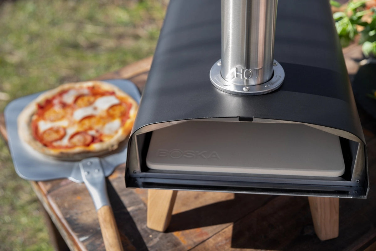 Schwarzer Pizzaofen für Pellets von Boska mit offener Feuertasse und Brennkammer, Grösse 69.9x36 cm, Höhe 72.5 cm.