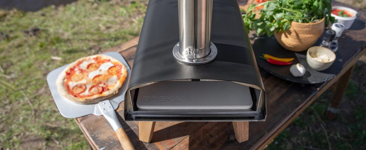 Schwarzer Pizzaofen für Pellets von Boska mit offener Feuertasse und Brennkammer, Grösse 69.9x36 cm, Höhe 72.5 cm.
