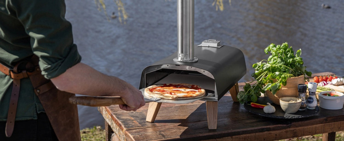 Schwarzer Pizzaofen für Pellets von Boska mit offener Feuertasse und Brennkammer, Grösse 69.9x36 cm, Höhe 72.5 cm.