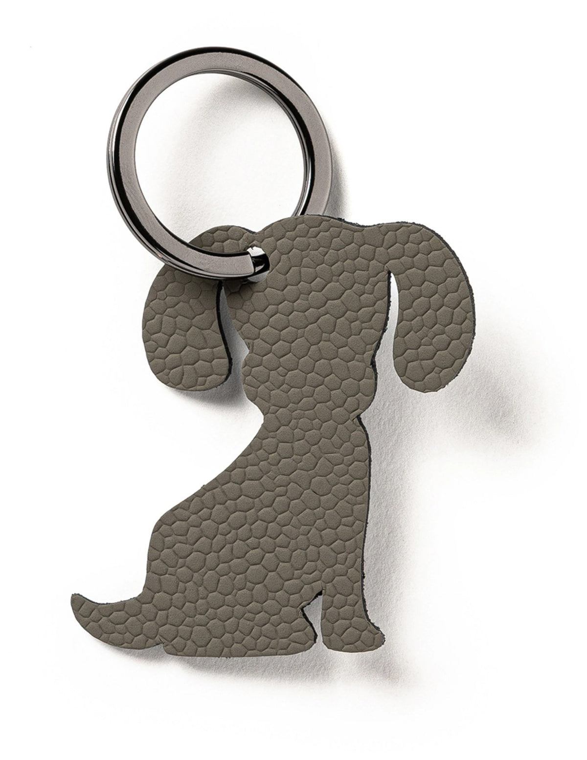 Grauer Schlüsselanhänger in Hundeform von MiLLE W NORDISK DESIGN, flache Form, Masse 7 x 5 x 0.2 cm, auf neutralem Hintergrund fotografiert.