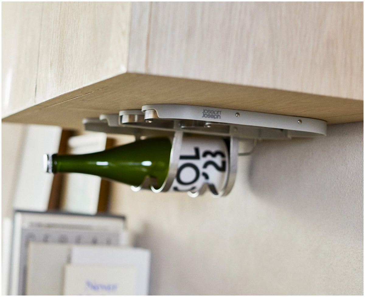 Klappbarer Weinflaschenhalter aus Edelstahl in Hellgrau, montiert unter einem Küchenschrank, mit Platz für vier Flaschen und Magnetverschluss.