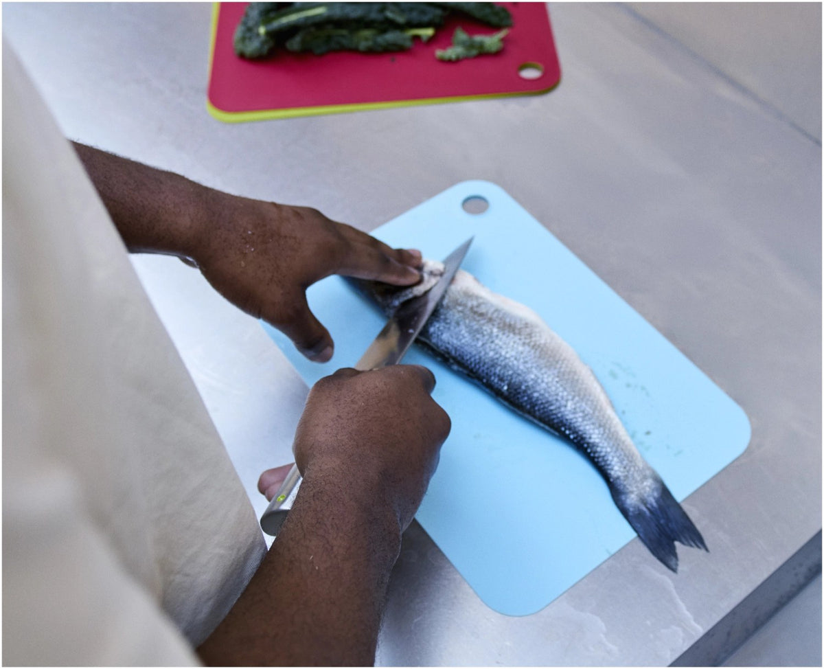 Drei bunte, kompakte Kunststoff-Schneidematten im Set, mit beidseitiger Schneidfläche und Klipp-Verschluss zur platzsparenden Aufbewahrung, Marke Joseph Joseph.