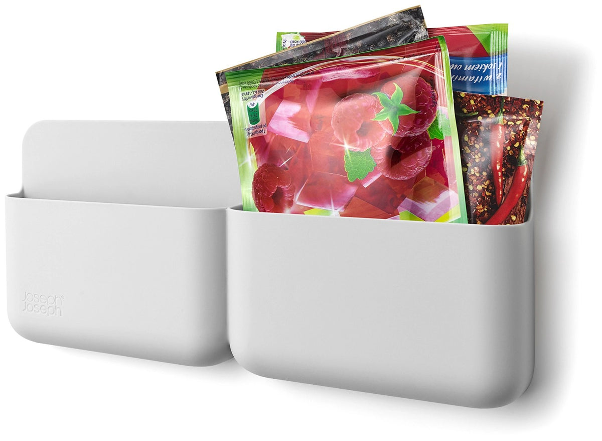 Graue Küchenhalterung für Tüten von Joseph Joseph, montiert an einer Schranktür, aus recyceltem Kunststoff mit Klebeband auf der Rückseite.