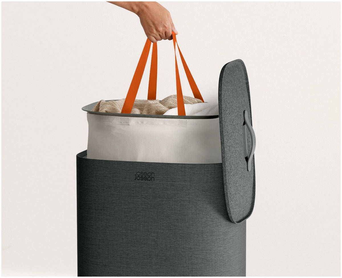 Grauer Wäschetrennkorb Tota One 60l von Joseph Joseph mit seitlichem Filzdeckel und herausnehmbarer Tragetasche für die Wäsche.