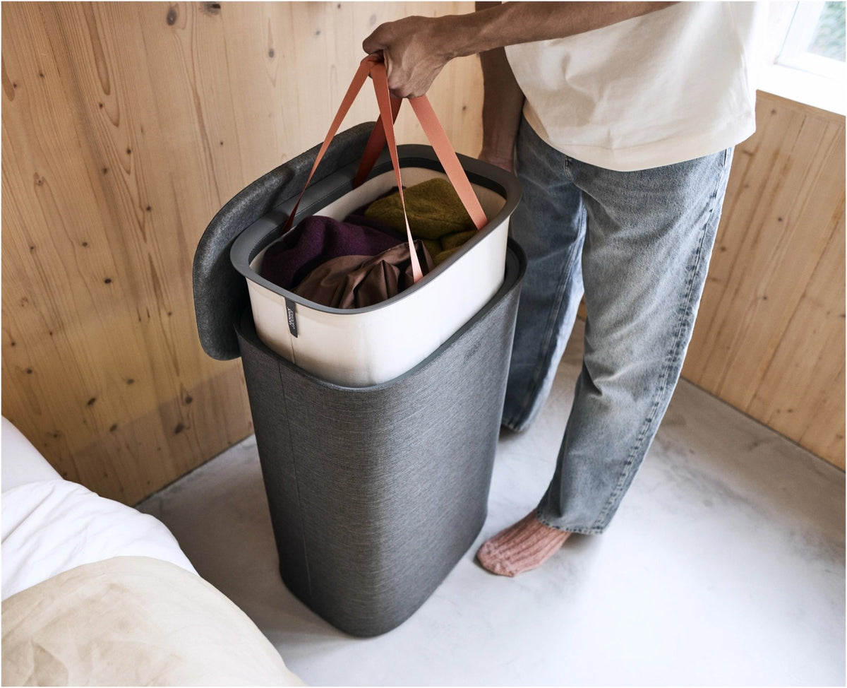 Grauer Wäschetrennkorb Tota One 60l von Joseph Joseph mit seitlichem Filzdeckel und herausnehmbarer Tragetasche für die Wäsche.