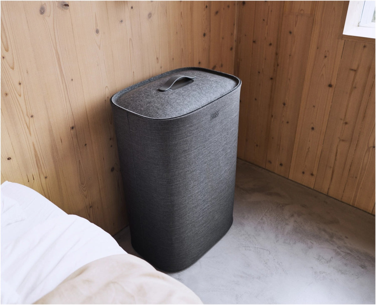 Grauer Wäschetrennkorb Tota One 60l von Joseph Joseph mit seitlichem Filzdeckel und herausnehmbarer Tragetasche für die Wäsche.
