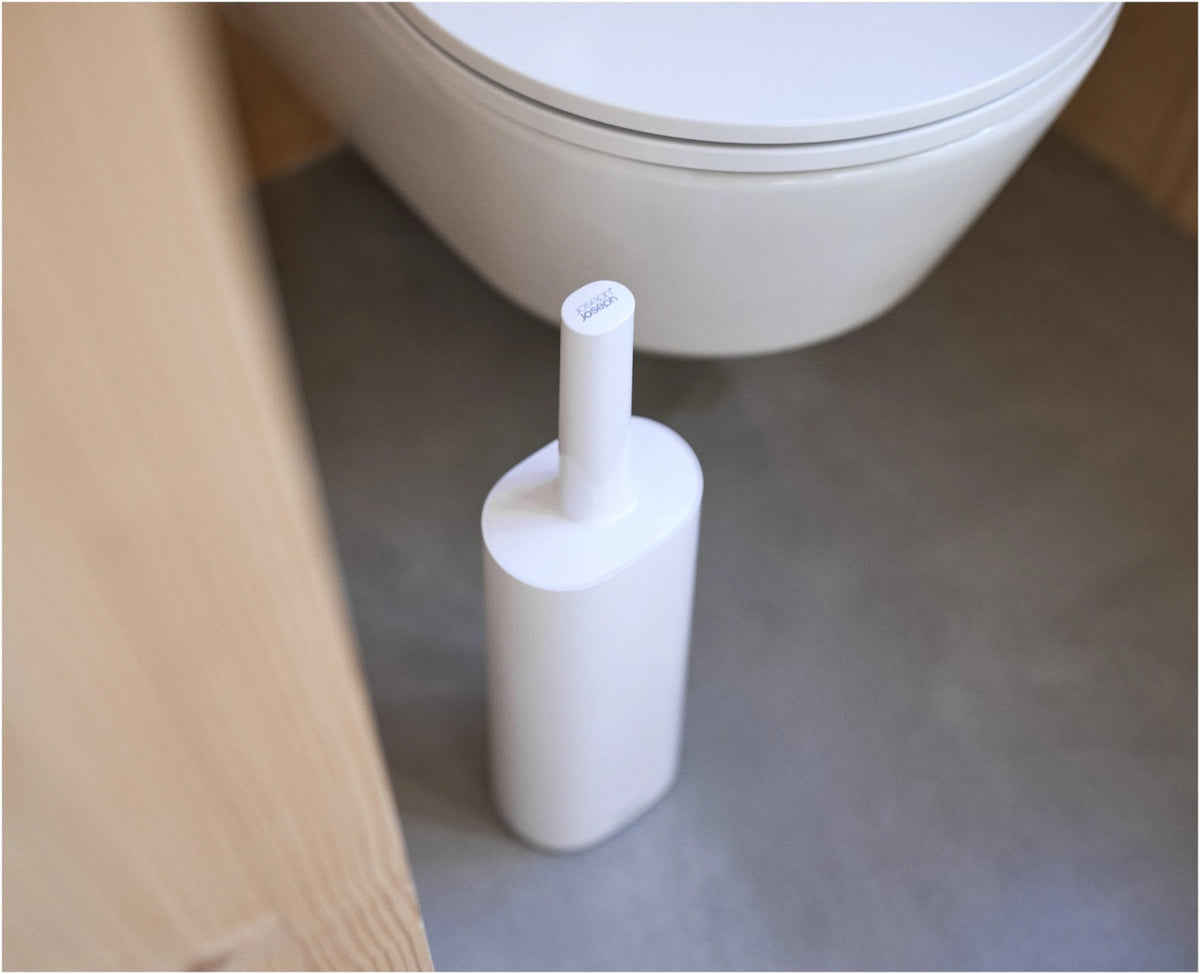 Weisse WC-Bürste Flex TriBlade von Joseph Joseph mit passendem geschlossenem Halter, schlanke Form, glänzende Oberfläche, freistehend im Badezimmer.