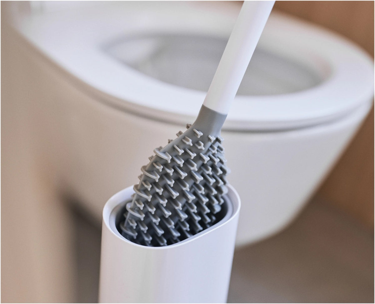 Weisse WC-Bürste Flex TriBlade von Joseph Joseph mit passendem geschlossenem Halter, schlanke Form, glänzende Oberfläche, freistehend im Badezimmer.