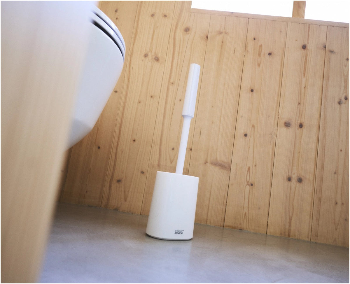 Weisse WC Bürste mit dreifach beklingten Borsten und passendem kompaktem Halter, glänzende Oberfläche, schlanke zylindrische Form.