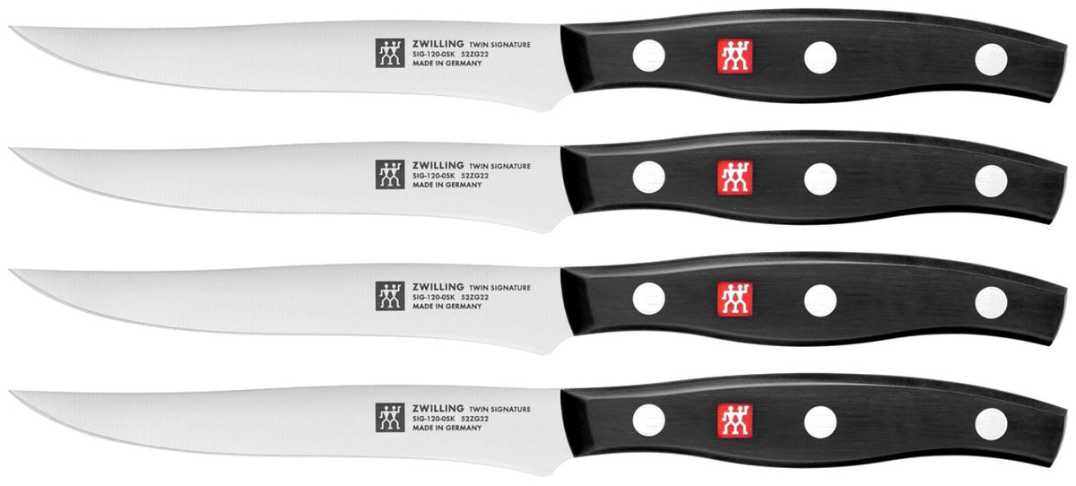 Vier Zwilling Signature Steakmesser mit 12cm Klinge aus Edelstahl, Griff im Drei-Nieten-Design, nebeneinander auf hellem Untergrund.
