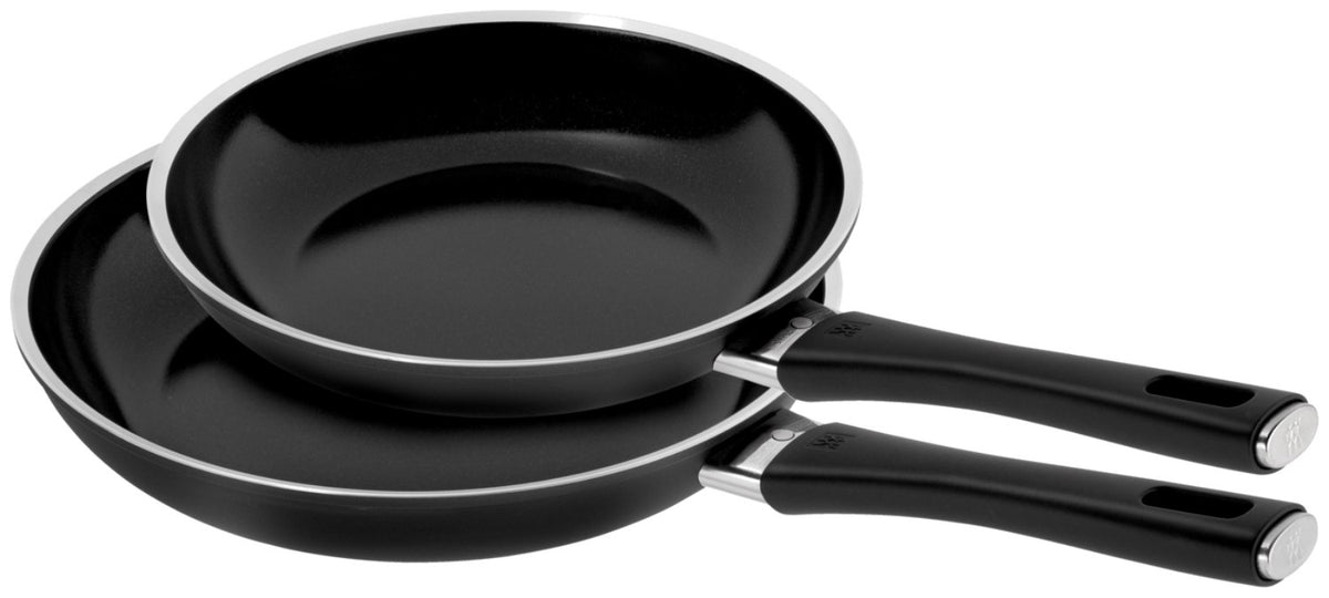 Zwei schwarze Bratpfannen aus Aluminium in den Grössen 24 und 28 cm mit Keramikbeschichtung und Griff, nebeneinander auf einer Fläche fotografiert.