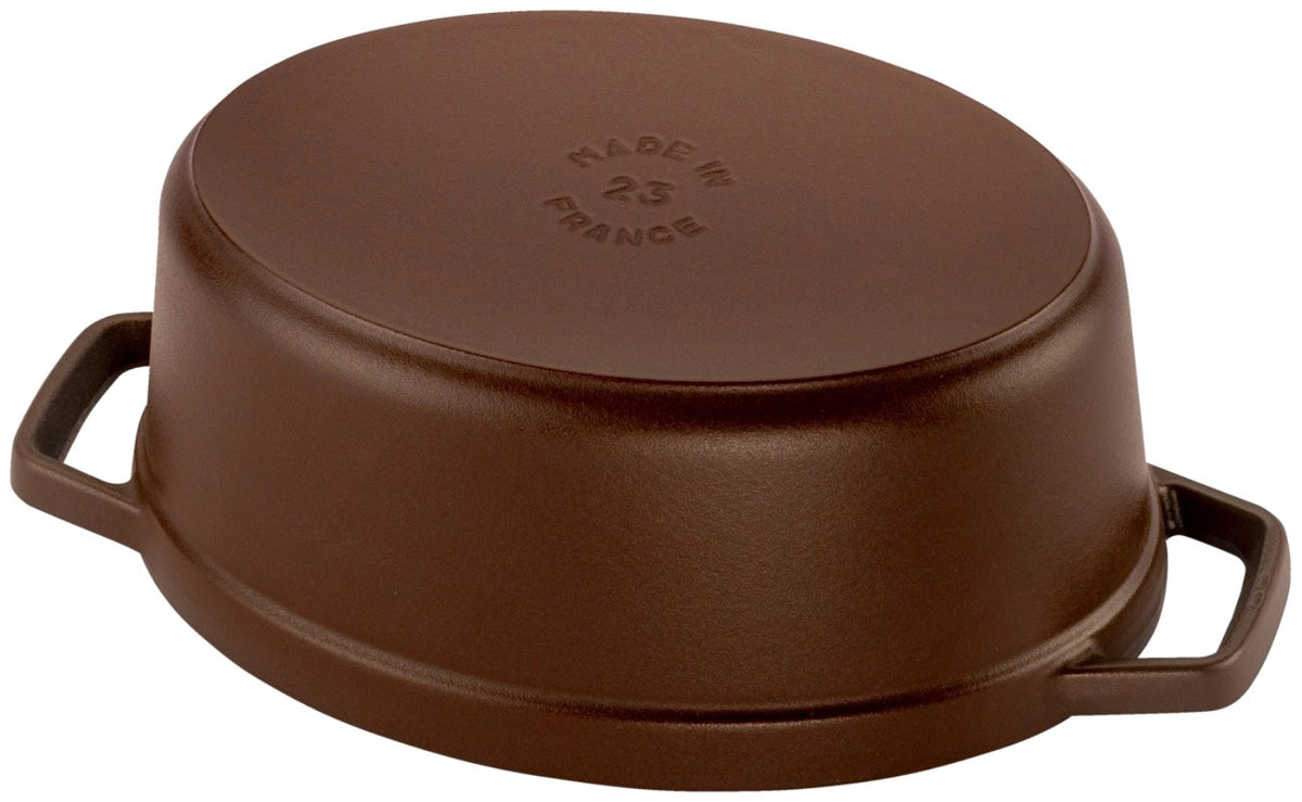 Ovale Staub Cocotte aus Gusseisen in brauner Emaille-Optik, 23 cm lang, mit Deckel und Tropfenstruktur auf der Innenseite.