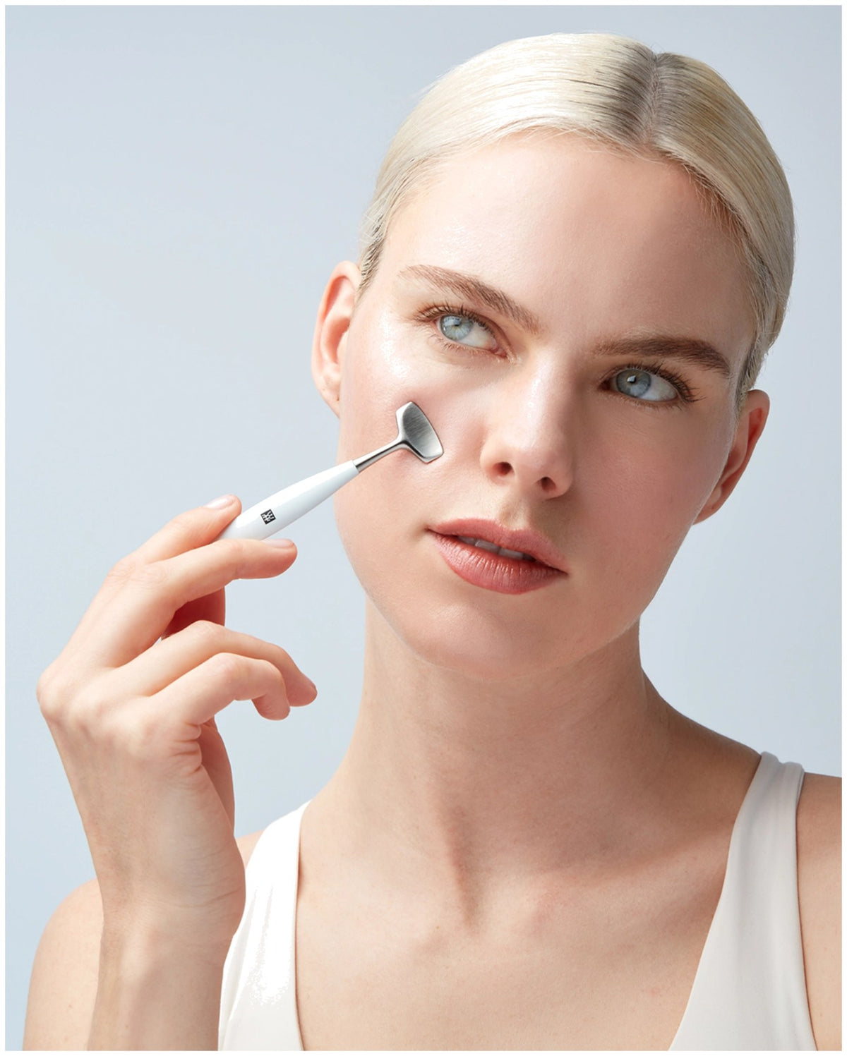 Silberfarbenes Facial Pore Refiner Tool aus Edelstahl mit zwei funktionalen Enden für die Gesichtspflege, liegend fotografiert.