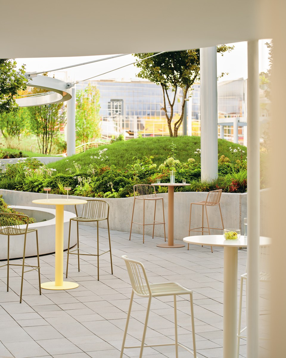 Zwei Barhocker mit durchbrochenem Sitz und Rückenlehne aus verzinktem Stahldraht, olivgrünes Gestell, schwarze Kunststofffüsse, Outdoor-Design.