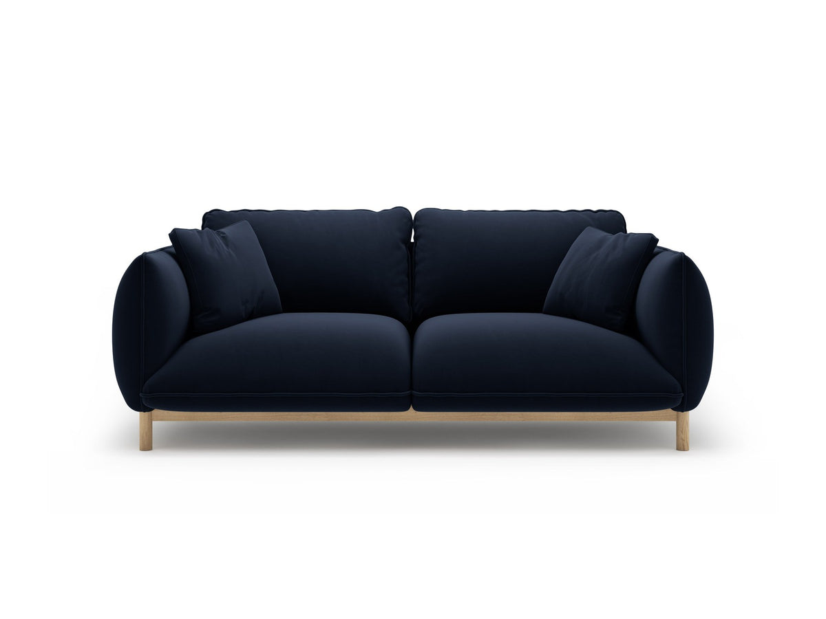 Ada 2er Sofa von Micadoni in Mandel beige mit gepolstertem Velours-Bezug, geschwungener Rückenlehne und sichtbaren Buchenholzbeinen.