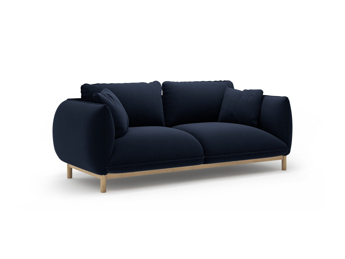 Ada 2er Sofa von Micadoni in Mandel beige mit gepolstertem Velours-Bezug, geschwungener Rückenlehne und sichtbaren Buchenholzbeinen.