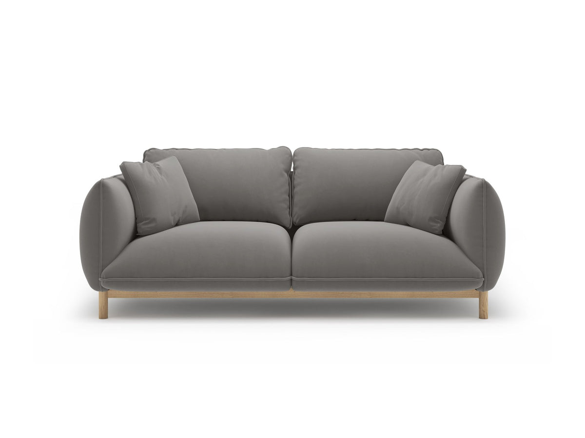 Ada 2er Sofa von Micadoni in Mandel beige mit gepolstertem Velours-Bezug, geschwungener Rückenlehne und sichtbaren Buchenholzbeinen.