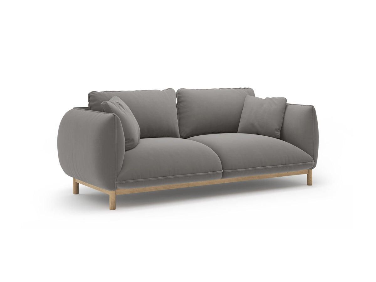 Ada 2er Sofa von Micadoni in Mandel beige mit gepolstertem Velours-Bezug, geschwungener Rückenlehne und sichtbaren Buchenholzbeinen.