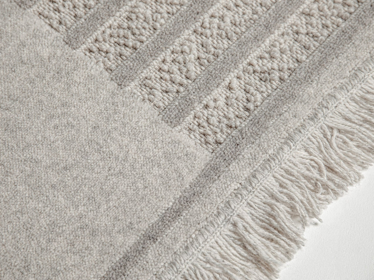Hellgrauer Wollteppich Form von Micadoni mit reliefartigem Muster aus Schnitt- und Schlingenflor, Grösse 230x160cm.