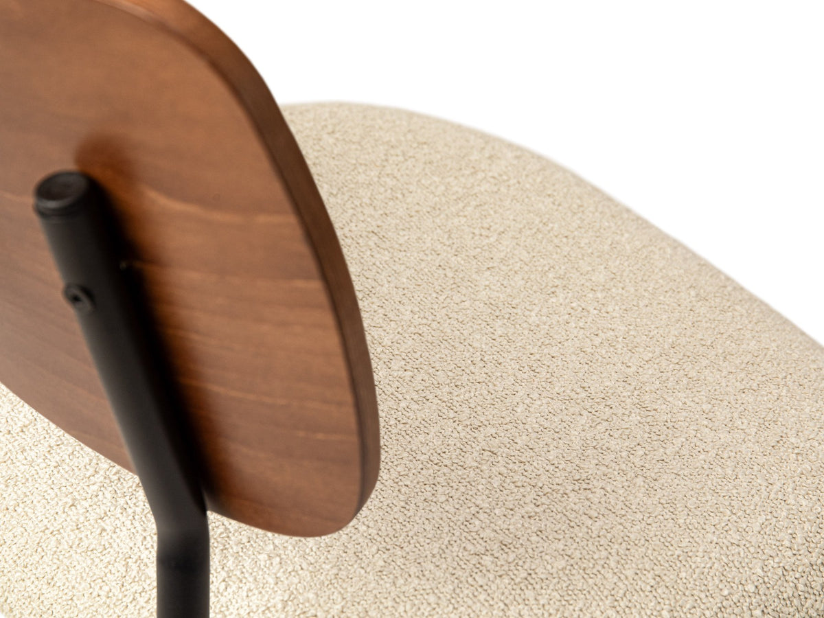 Beiger Samtstuhl mit gepolstertem Sitz aus Bouclé-Stoff, ergonomischer Rückenlehne aus Buchenholz und schwarzen Stahlbeinen im Esszimmer.