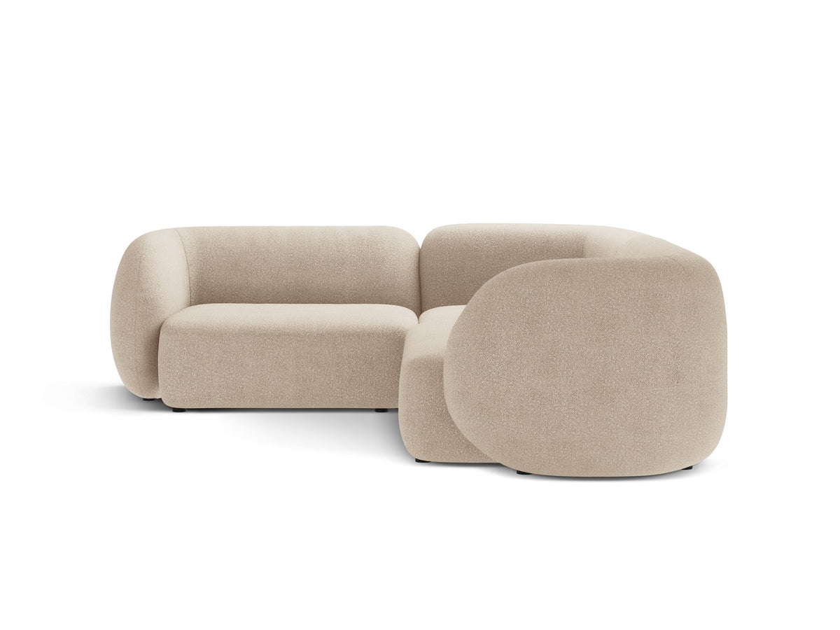 Weisses Ecksofa links Kate von Micadoni mit Bouclé-Stoff Baloo, schwarzen Kunststoffbeinen und niedriger Rückenlehne im Wohnraum.