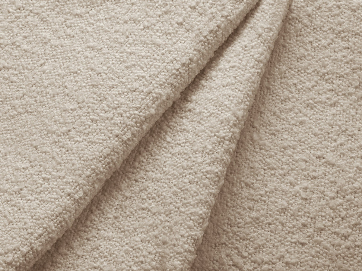 Weisses Ecksofa links Kate von Micadoni mit Bouclé-Stoff Baloo, schwarzen Kunststoffbeinen und niedriger Rückenlehne im Wohnraum.
