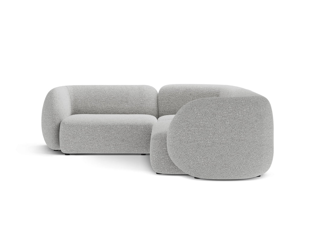 Weisses Ecksofa links Kate von Micadoni mit Bouclé-Stoff Baloo, schwarzen Kunststoffbeinen und niedriger Rückenlehne im Wohnraum.