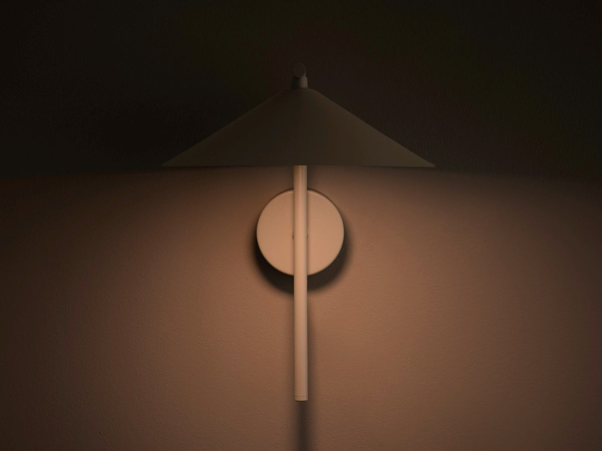 Wandlampe Nocte von Micadoni in Burgundfarben, konische Form aus mattem Metall, montiert an einer hellen Wand im Wohnraum.