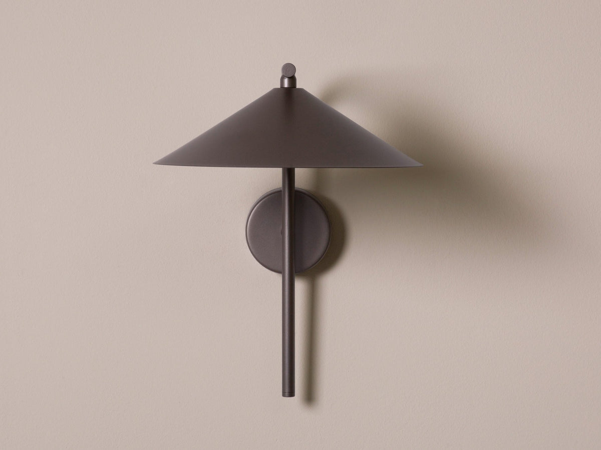 Wandlampe Nocte von Micadoni in Burgundfarben, konische Form aus mattem Metall, montiert an einer hellen Wand im Wohnraum.