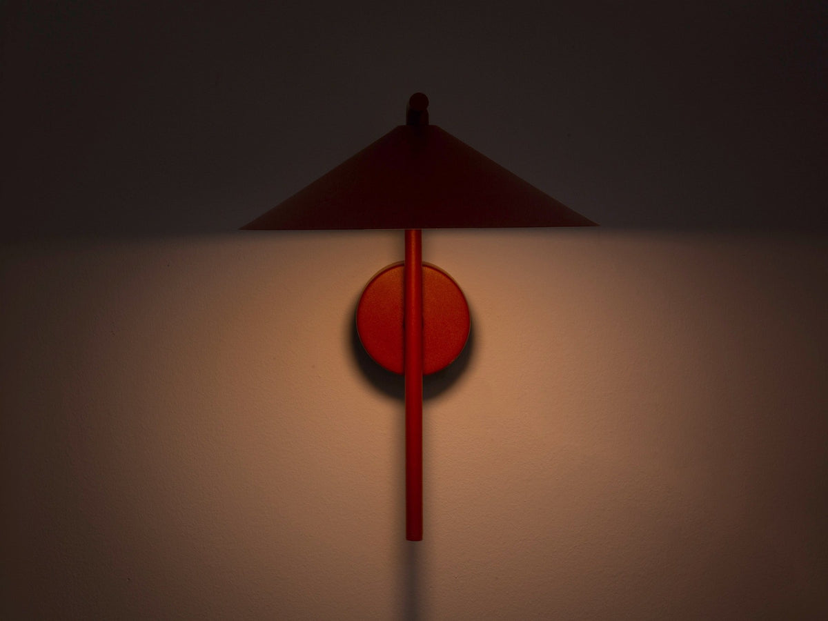 Wandlampe Nocte von Micadoni in Burgundfarben, konische Form aus mattem Metall, montiert an einer hellen Wand im Wohnraum.