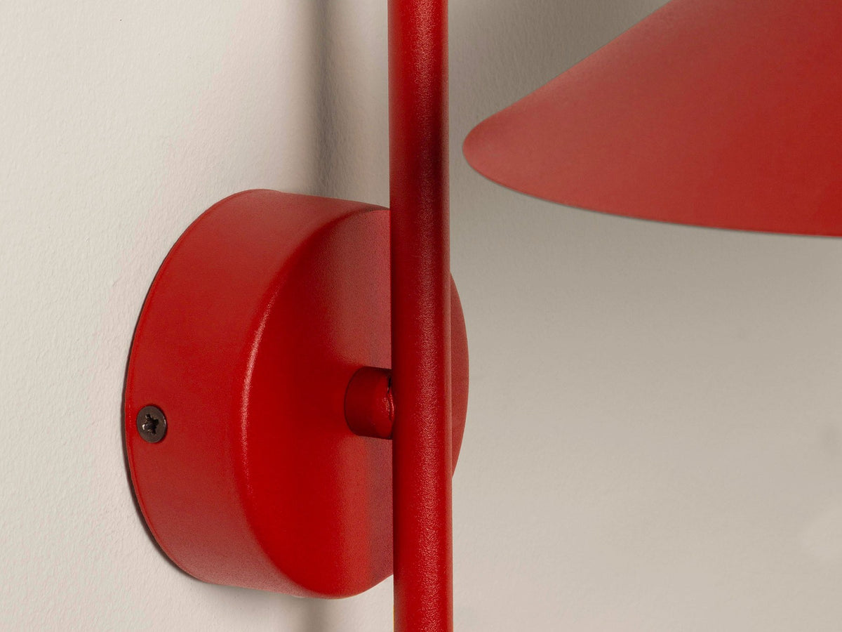 Wandlampe Nocte von Micadoni in Burgundfarben, konische Form aus mattem Metall, montiert an einer hellen Wand im Wohnraum.