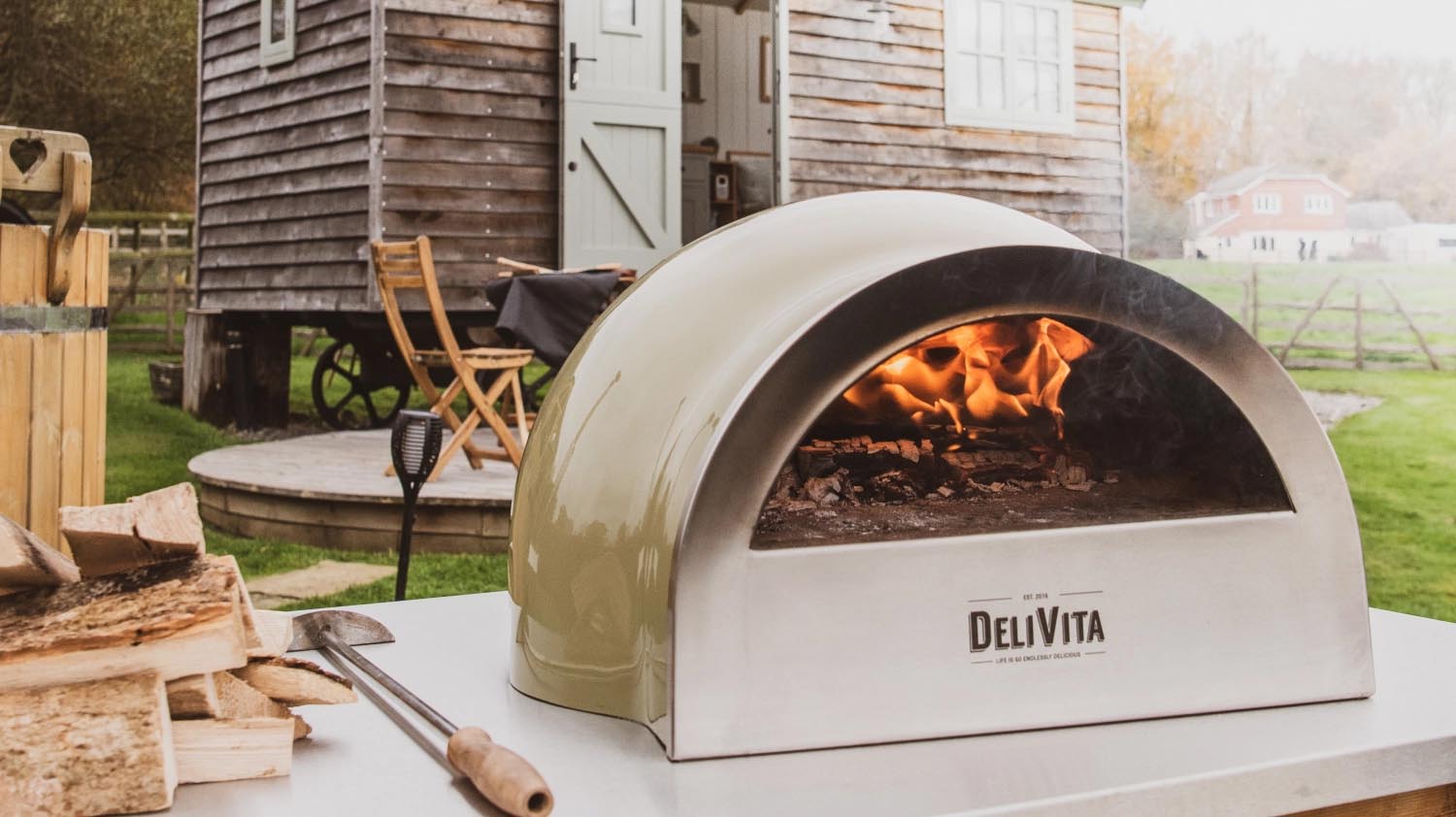 Der olivgrüne Delivita Holzofen ist stilvoll und vielseitig, ideal für Pizza und Outdoor-Kochen im Garten.