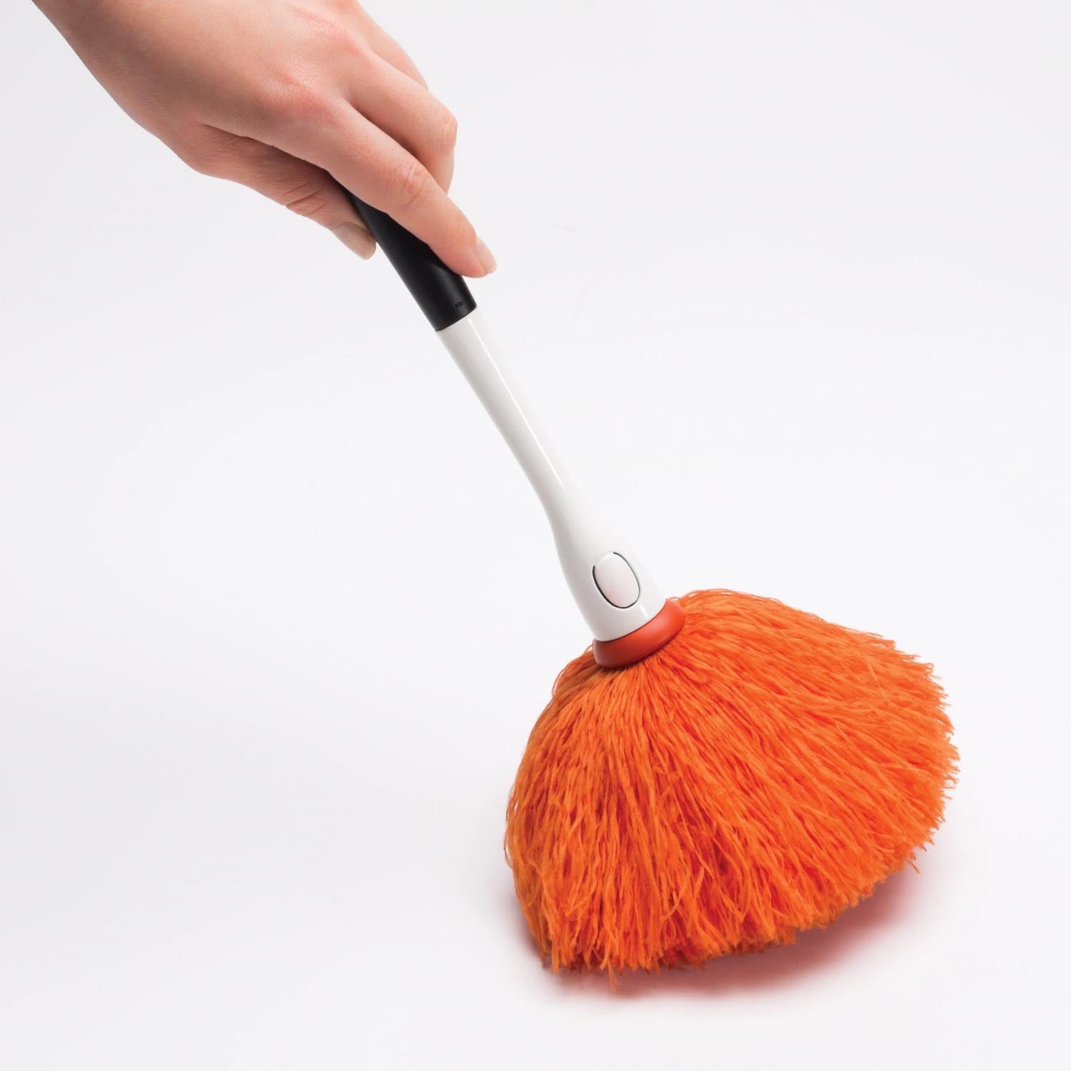 Kleiner, orangefarbener Staubwedel von OXO Good Grips, perfekt für präzises Staubwischen dank ergonomischem Griff und sanften Borsten.