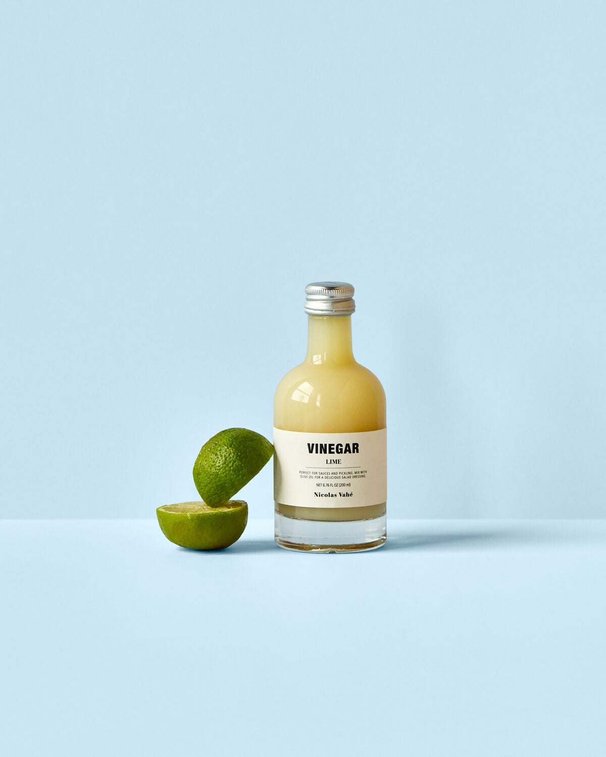 Flasche mit 200 ml Limettenessig von Nicolas Vahé, stilvoll präsentiert auf einem Holzuntergrund, ideal für kreative Küche.