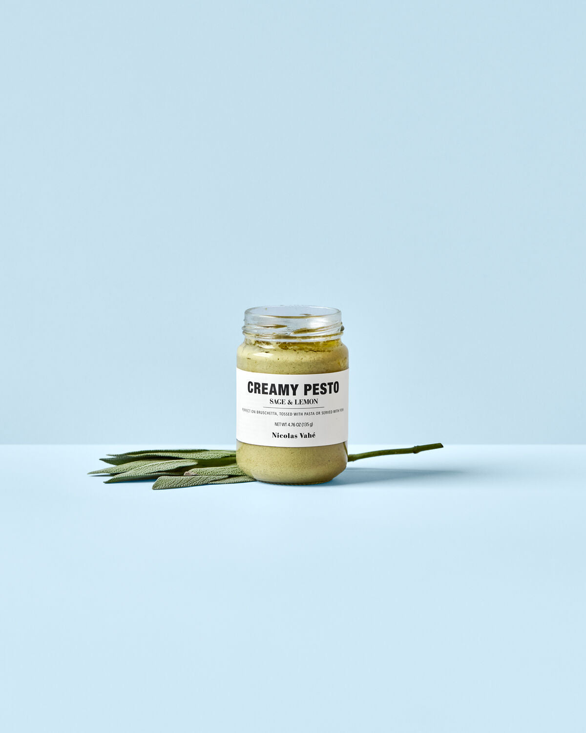 Ein Glas mit cremigem Pesto aus Salbei und Zitrone, 135 g, von Nicolas Vahé, stilvoll präsentiert auf einem Holzbrett.