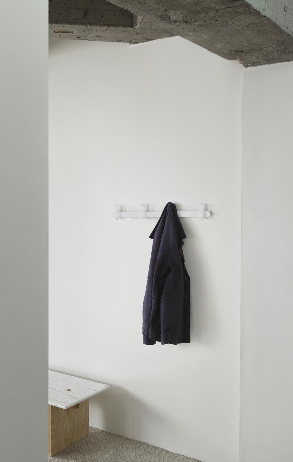 Weisse Hoop Wandgarderobe von Normann Copenhagen mit ringförmigen Kleiderhaken aus Esche und Stahl, montiert an einer Wand.