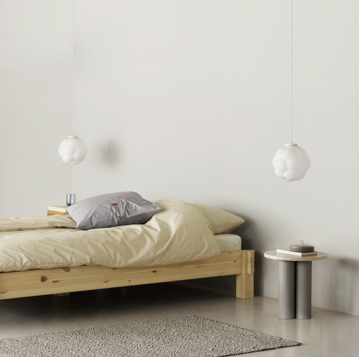 Beistelltisch Dit von Normann Copenhagen mit runder Tischplatte aus Stein in Sand Travertine Light, getragen von drei zylindrischen Stahlbeinen.