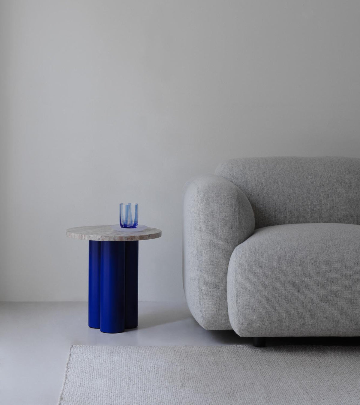 Beistelltisch Dit von Normann Copenhagen mit runder Tischplatte aus Stein in Sand Travertine Light, getragen von drei zylindrischen Stahlbeinen.