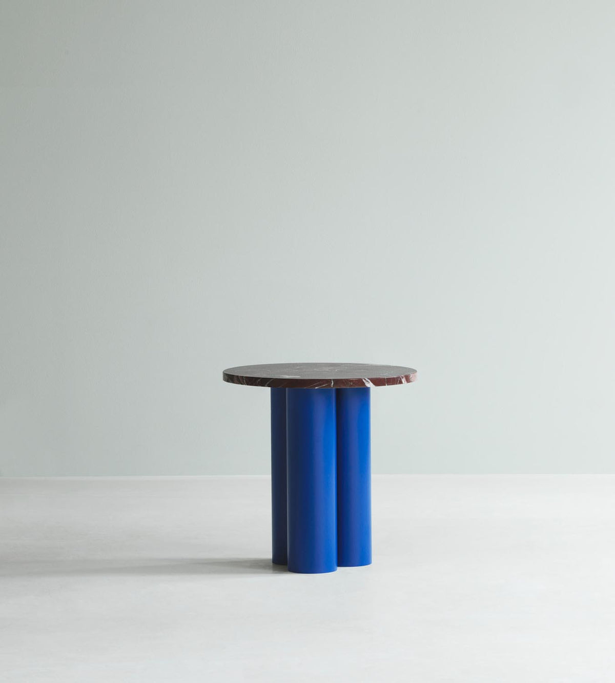 Beistelltisch Dit von Normann Copenhagen mit runder Tischplatte aus Stein in Sand Travertine Light, getragen von drei zylindrischen Stahlbeinen.