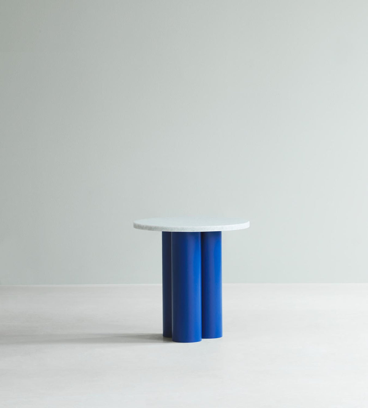 Beistelltisch Dit von Normann Copenhagen mit runder Tischplatte aus Stein in Sand Travertine Light, getragen von drei zylindrischen Stahlbeinen.
