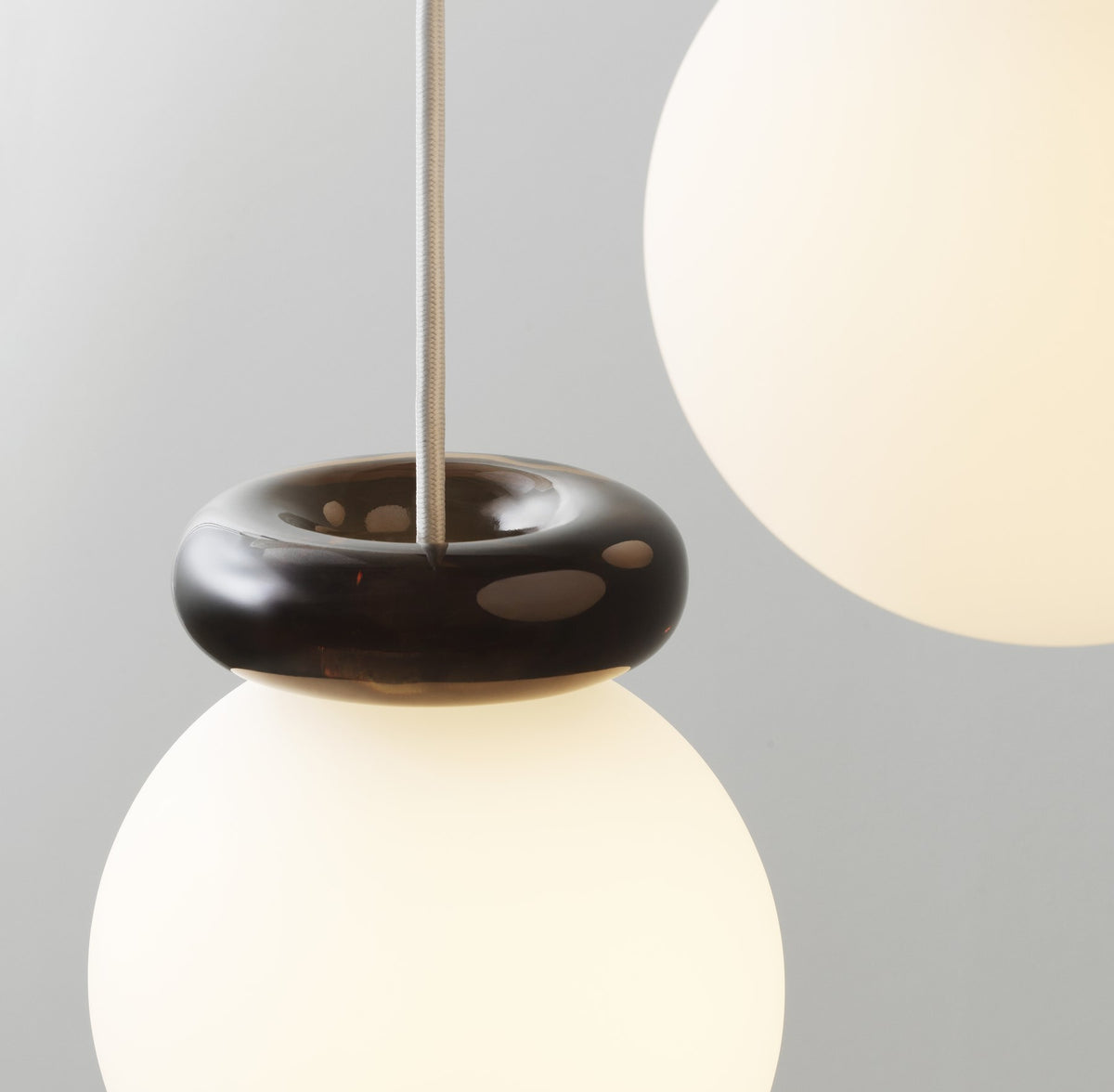 Pendelleuchte Hinx von Normann Copenhagen in Dunkelbraun, Lampenschirm aus Opalglas mit ringförmigem Kunstharzsockel.