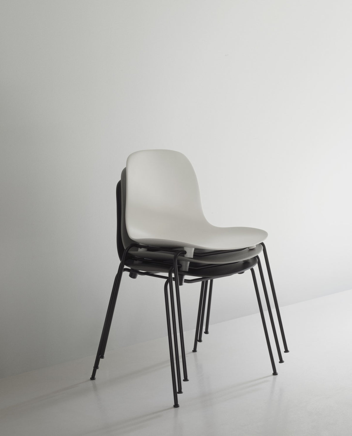 Form Stapelstuhl von Normann Copenhagen in Schwarz, gepolsterte Sitzschale aus Polypropylen auf vierbeinigem Gestell aus pulverbeschichtetem Stahl.