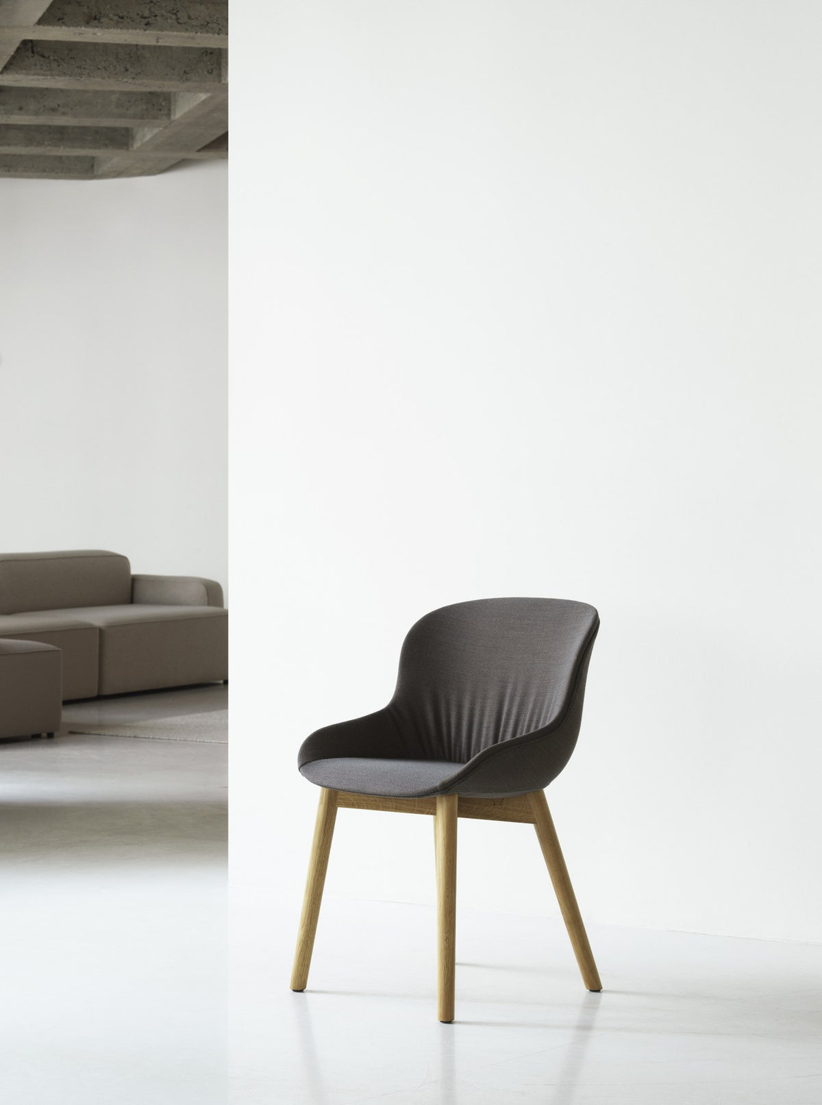 Vollgepolsterter Esszimmerstuhl Hyg Comfort von Normann Copenhagen in Grau, mit gedrechselten Beinen aus lackierter Eiche und weich drapierter Rückenlehne.