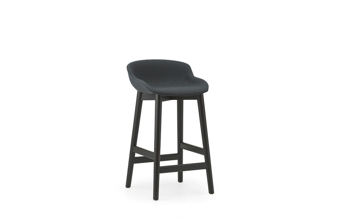Hyg Barhocker von Normann Copenhagen mit vollständig gepolsterter Sitzschale aus Polypropylen, Gewebebezug UDA25 und lackierten Beinen aus Eiche, Sitzhöhe 65 cm.