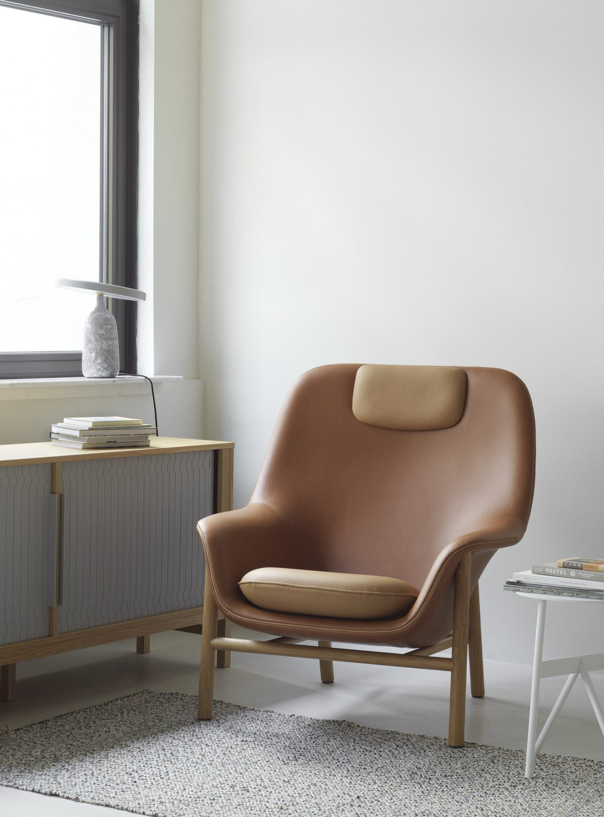 Drape Lounge-Sessel von Normann Copenhagen in Cognac mit hoher Rückenlehne, gepolsterter Sitzschale und Beinen aus Eichenholz.